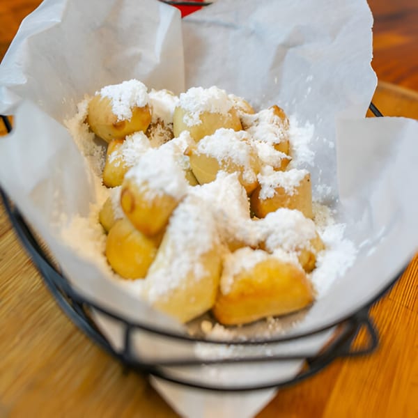 A basket of golden-brown, powdered sugar-dusted dessert knots from East Hill Pizza.
