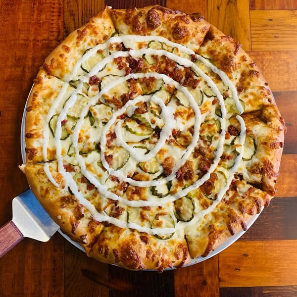 East Hill Pizza's dill pickle pizza, topped with bacon and a spiral of white sauce.