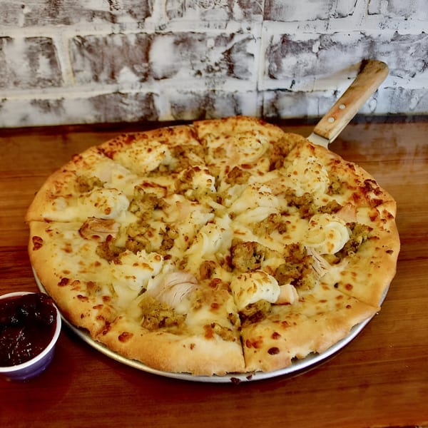 East Hill Pizza's white pizza with chicken and stuffing, served with a side of cranberry sauce.