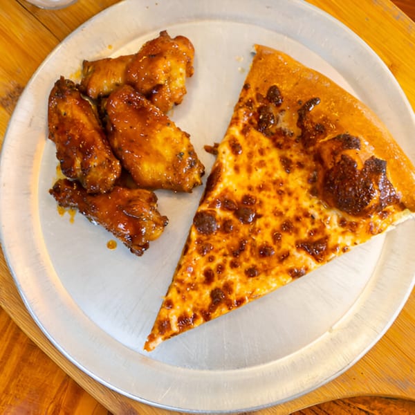 A slice of East Hill Pizza cheese pizza and several glazed chicken wings on a metal tray.